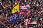 Supporters listen as President Donald Trump speaks as a Confederate-themed and other flags flutter in the wind during a rally in Washington.