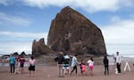 People couldn't get too close to Haystack Rock at Cannon Beach on Sunday like they did in this 2021 file photo. Parts of the beach were closed Sunday when a cougar was sighted on the rock, but the popular tourist destination reopened Monday after tracks were found that indicated it had left the area.