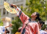 Dancers perform traditional fan dancing while on stage.