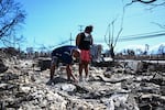 Davilynn Severson and Hano Ganer look for belongings through the ashes of their family's home on Friday in the aftermath of a wildfire in Lahaina, in western Maui, Hawaii.