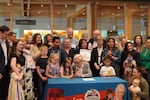 Gov. Tina Kotek signs legislation codifying the Dolly Parton Imagination Library into state law, joined by families and supporters of the program in a Gresham library.