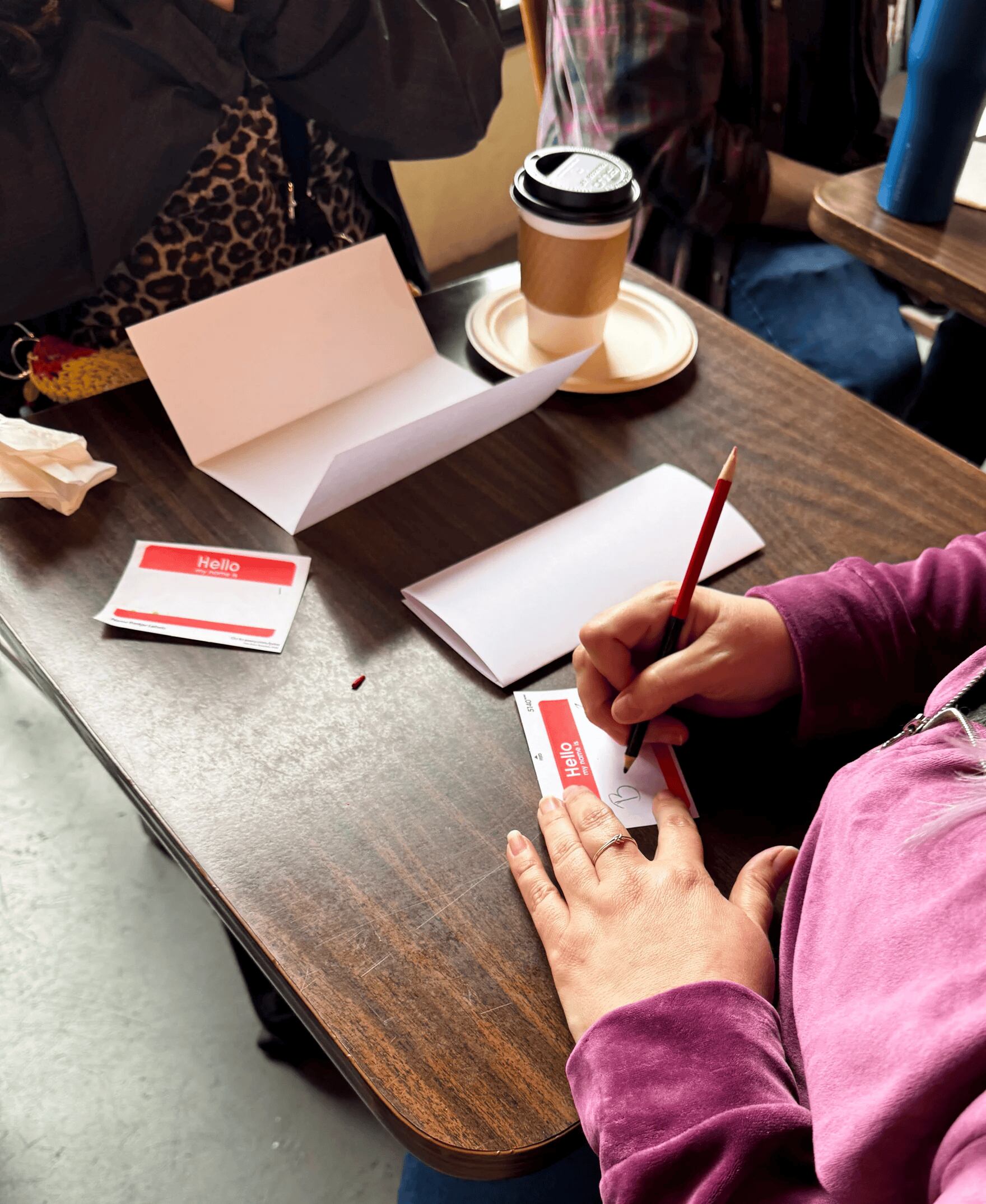 Participants at Cafe Con Arte’s speed-friending event on March 13, 2026, fill out name tags before they speak with others in the room.