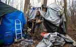 Jose Ortiz eats a boxed meal delivered by volunteers to the residence he built in the homeless encampment known as the Jungle on Monday, Dec. 7, 2020, in Ithaca, N.Y.