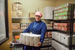 Trenna Wilson, a PSU student and general manager of the university's food pantry, stands holding packs of flour in an extra storage closet around the corner from the main small pantry space on Dec. 12, 2022.