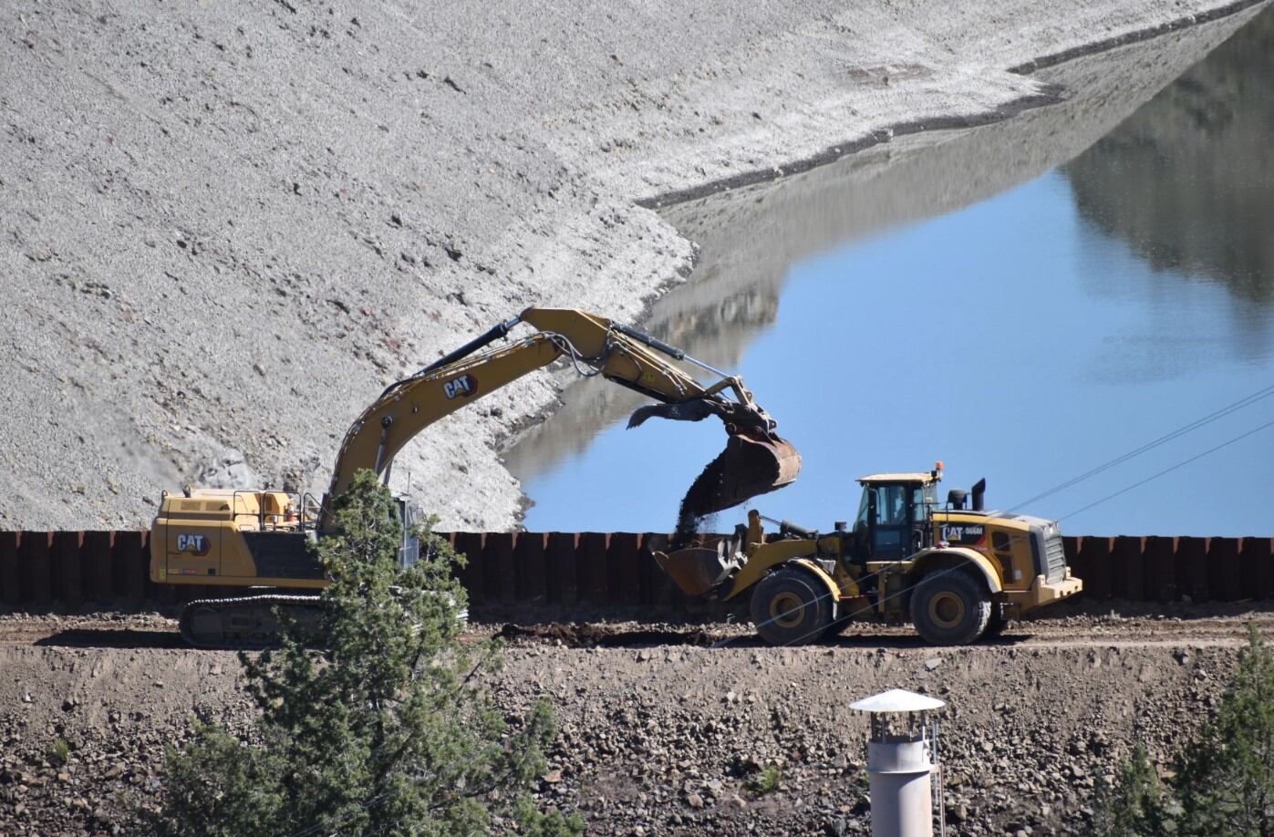 Heavy machinery removing the first scoop of dirt from Iron Gate dam on May 1, 2024.