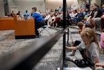 Portland Association of Teachers President Alisha Chavez gives testimony, left, as children play while attending the meeting.