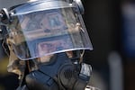 A National Guard officer wearing a helmet with visor and a gas mask stands guard at the Metropolitan Detention Center during an anti-ICE protest in downtown Los Angeles on Sunday.