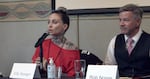 Two people sit next to each other at a long table, with microphones in front of each. One has the name tag "Elle Stranger," and the other has the name tag "Rob Nosse"