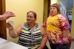 Esther Bodine, left, receives her ticket, marking how many people there are in her household, after she and her sister, Rachel Cooper, right, check into the Dallas Food Bank. The food bank has two intake stations now due to increased need.