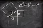 This photo shows a blackboard on which is written in white chalk: a^2 + b^2 = c^2. Also drawn on the chalkboard is a right triangle with its sides labeled a, b and c and with each side forming one side of a square that extends out from that side of the triangle.
