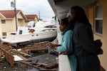 Frankie Romulus (left) and Kendrick Romulus stand on Sept. 29, 2022, outside their apartment in Fort Myers, Fla., next to a boat that floated into their complex when Hurricane Ian passed through the area.