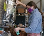 Wellspent Market’s Hannah Cable tips a drum of olive oil to fill a bottle at the Portland shop, Oct. 8, 2021. The store’s once yearly olive oil delivery from Italy has been stuck in transit for months. 