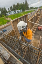 A sticker that reads "gender roles are dead" is on the helmet of a construction crew member working on new retaining wall in Tigard on May 23, 2024.