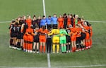 National Women's Soccer league players form a circle on the pitch at Providence Park in Portland.