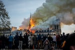 People watch the landmark Notre-Dame Cathedral burning in central Paris on April 15, 2019- A fire broke out at the landmark Notre-Dame Cathedral in central Paris, potentially involving renovation works being carried out at the site, the fire service said. (Photo by Nicolas Liponne/NurPhoto via Getty Images)