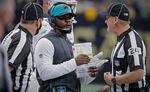 FILE - Miami Dolphins head coach Brian Flores, center, talks to down judge David Oliver (24) during the first half of an NFL football game against the New Orleans Saints Monday, Dec. 27, 2021, in New Orleans. Fired Miami Dolphins Coach Brian Flores sued the NFL and three of its teams Tuesday, Feb. 1, 2022 saying racist hiring practices by the league have left it racially segregated and managed like a plantation. (AP Photo/Butch Dill, File)