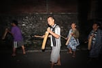 Four Indonesian Muslim men walking outdoors in the dark use sticks to strike kentongans, which are traditional wooden drums, to wake people up for sahur, the early-morning pre-fast meal during Ramadan, on July 3, 2014, in Semarang, Central Java.