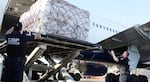 U.S. Customs and Border Protection says it processes some 4 million de minimis shipments every day. Here, CBP officers watch as international shipments are lowered from a plane at Los Angeles International Airport.