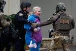 A demonstrator is detained outside a U.S. Immigration and Customs Enforcement facility during a protest on Saturday, Oct. 11, 2025, in Portland, Ore.