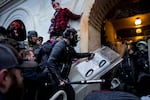 Trump supporters, including one holding a baseball bat and grabbing a police shield, clash with police and security forces outside a tunnel into the U.S. Capitol.