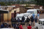 South African police gather at the scene of a mass shooting where gunmen killed nine and injured at least 10 in a pub in Bekkersdal, South Africa, Sunday, Dec. 21, 2025.