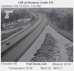 An aerial view of an interstate shows snow next to the traffic lanes but not on the roadway in a black and white photo.