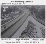 An aerial view of an interstate shows snow next to the traffic lanes but not on the roadway in a black and white photo.