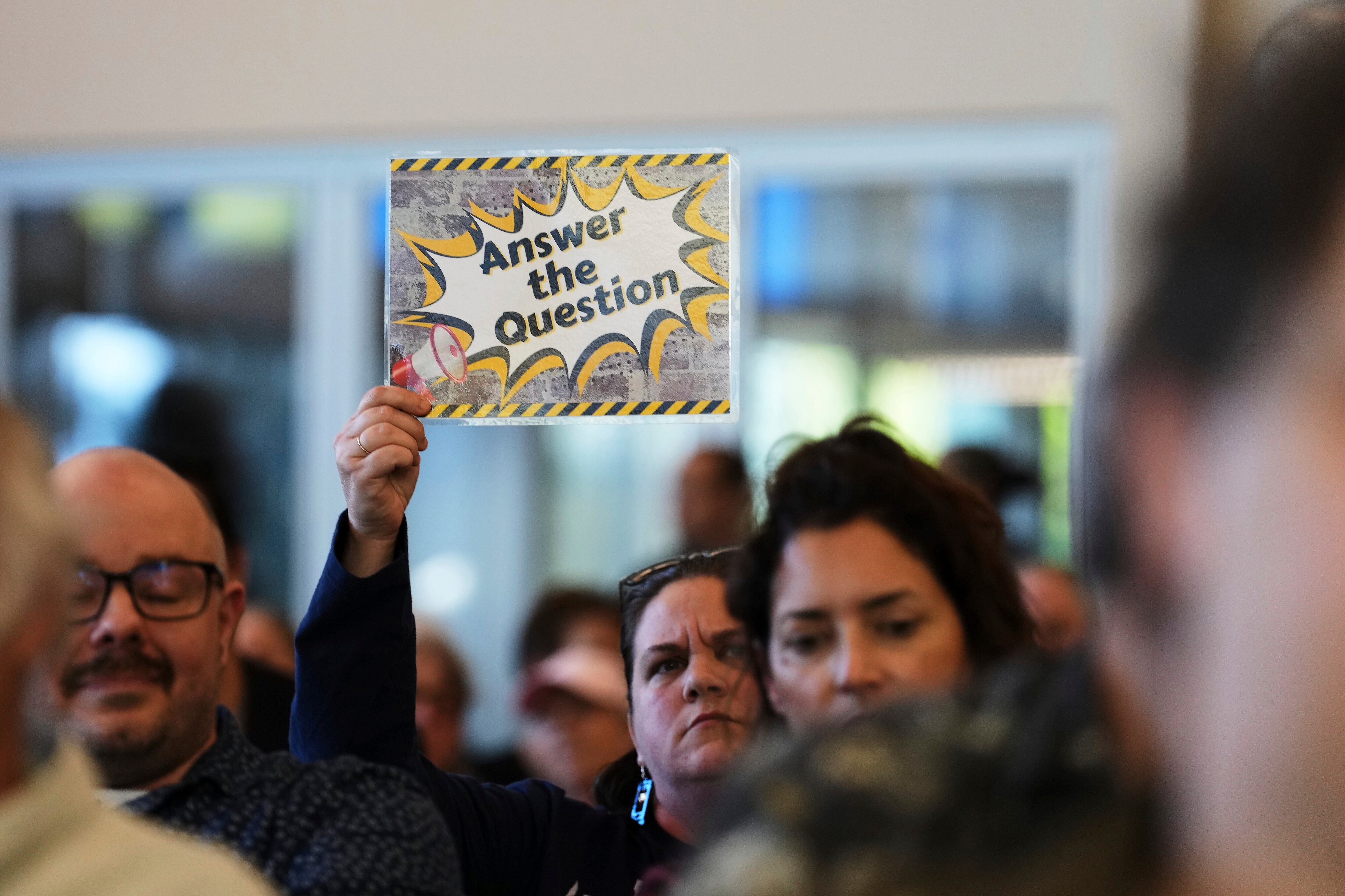 Liz Oxford holds up a sign during the town hall event.