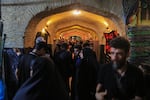 Pilgrims pass through a historic vaulted passage decorated with religious flags and banners