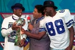 Dallas Cowboys cornerback Deion Sanders (left) and running back Michael Irvin (88) share the Vince Lombardi trophy as NBC commentator Greg Gumbel interviews the two after Super Bowl XXX in Tempe, Ariz., on Jan. 28, 1996.