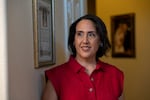 Raquel Salas stands next to a framed Catholic blessing and in front of her wedding portrait, at her home in Phonenix, AZ.