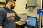 OSU researcher Byrne Miyamoto monitors how much weight a piece of Western Juniper can hold.