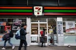 People walk past a 7-Eleven convenience store in New York City on Wednesday. The company plans to shut down 444 stores across North America to recoup costs lost to inflation, a drop in store traffic and declining cigarette sales.