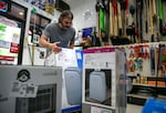 Matt Ellis, an employee of Hankins Hardware True Value in northeast Portland, Ore., arranges a display of air conditioners at the front of the store on July 3, 2024. With temperatures expected to reach triple digits over the holiday weekend, Ellis says he expects the store will sell out of fans and air conditioners.