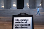 A woman walks past a sign indicating the National Gallery of Art in Washington, D.C., is closed as the federal government continues its shutdown.