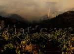 A firefighting helicopter drops water onto the Pickett Fire as it burns in the hills near a vineyard on Aug. 21, 2025 in Calistoga, California.
