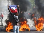 A demonstrator holds up an Haitian flag during protests demanding the resignation of Prime Minister Ariel Henry in Port-au-Prince, Haiti, Friday, March 1, 2024.