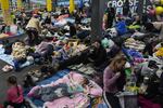 People sit and lie on the floor in the improvised bomb shelter in a sports center, which can accommodate up to 2000 people, in Mariupol, Ukraine, late Sunday, Feb. 27, 2022. Explosions and gunfire that have disrupted life since the invasion began last week appeared to subside around Kyiv overnight, as Ukrainian and Russian delegations prepared to meet Monday, Feb. 28, 2022 on Ukraine's border with Belarus. It's unclear what, if anything, those talks would yield. Terrified Ukrainian families huddled in shelters, basements or corridors, waiting to find out. (AP Photo/Evgeniy Maloletka)