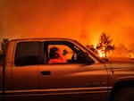 Andrea Douglas holds her head while evacuating as the Park Fire jumps Highway 36 near Paynes Creek in Tehama County, Calif., on Friday.