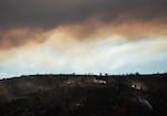 Fires burn on a charred hillside off NW Pelton Dam Road between Warm Springs and Madras, Ore., as thick smoke rises beyond from the Bench Fire on July 27, 2026.