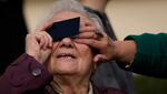 An elderly woman looks through a welding filter during a partial solar eclipse in Bucharest, Romania, Oct. 25, 2022.