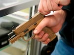 A worker clears a handgun for a customer at Davidson Defense in Orem, Utah, in 2021.