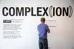 Dan Ling hangs a bracket for the Be Nice (White) You're In Bend exhibit at Scalehouse in Bend, Ore., Friday, Aug. 6, 2021.