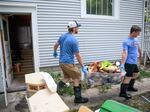 Jared Gerlock (left) and his son, Robbie, carry a bin of water-logged stuffed animals out of the flood-damaged basement of their home on East Second Street in Spencer, Iowa, on Tuesday. Officials said about 40% of properties in the city were affected after the Little Sioux River flooded. 