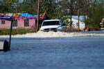 A truck drives through a flooded street in Lake Charles, La., Saturday, Oct. 10, 2020, past a home with damage from Hurricane Laura, after Hurricane Delta moved through on Friday. 