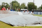 Boston Hunters and San Francisco Firebells players assist the grounds crew in rolling up the infield tarp at Robin Roberts Stadium prior to the start of the inaugural game of the Women's Pro Baseball League. Springfield, IL, August 1, 2026.