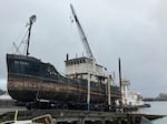 A ship rests on wheels on a dock.