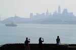 People take pictures at a vista point with the San Francisco skyline obscured by smoke from wildfires during a spate of smoke during 2020, one of the worst wildfire smoke years on record.