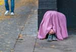 FILE-A person huddles under a blanket in downtown Portland, Ore., Nov. 15, 2023. Portland Mayor Keith Wilson aims to open 3,000 new shelter beds by December, to support the nearly 6,000 people living unsheltered in Multnomah County. 