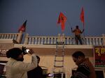 Men place celebratory flags on a building in the northern Indian city of Ayodhya, where the new Hindu temple will be consecrated on Monday.